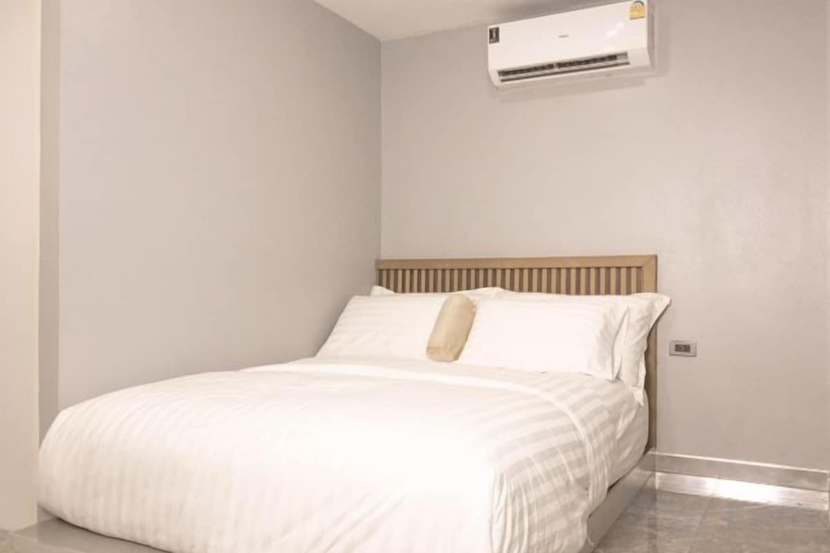 A bedroom with a bed, a headboard, and an air conditioning unit mounted on the wall.