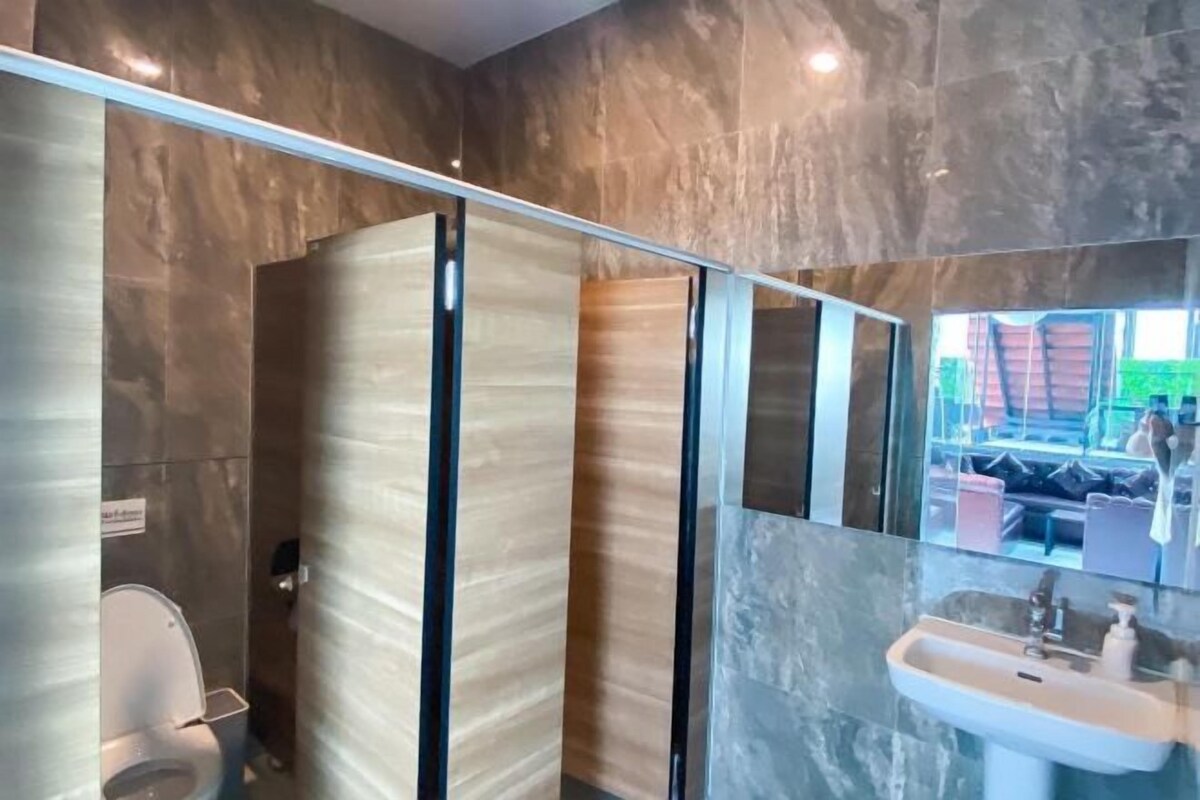 A modern bathroom with a glass shower enclosure, a toilet, and a sink with a mirror above it.