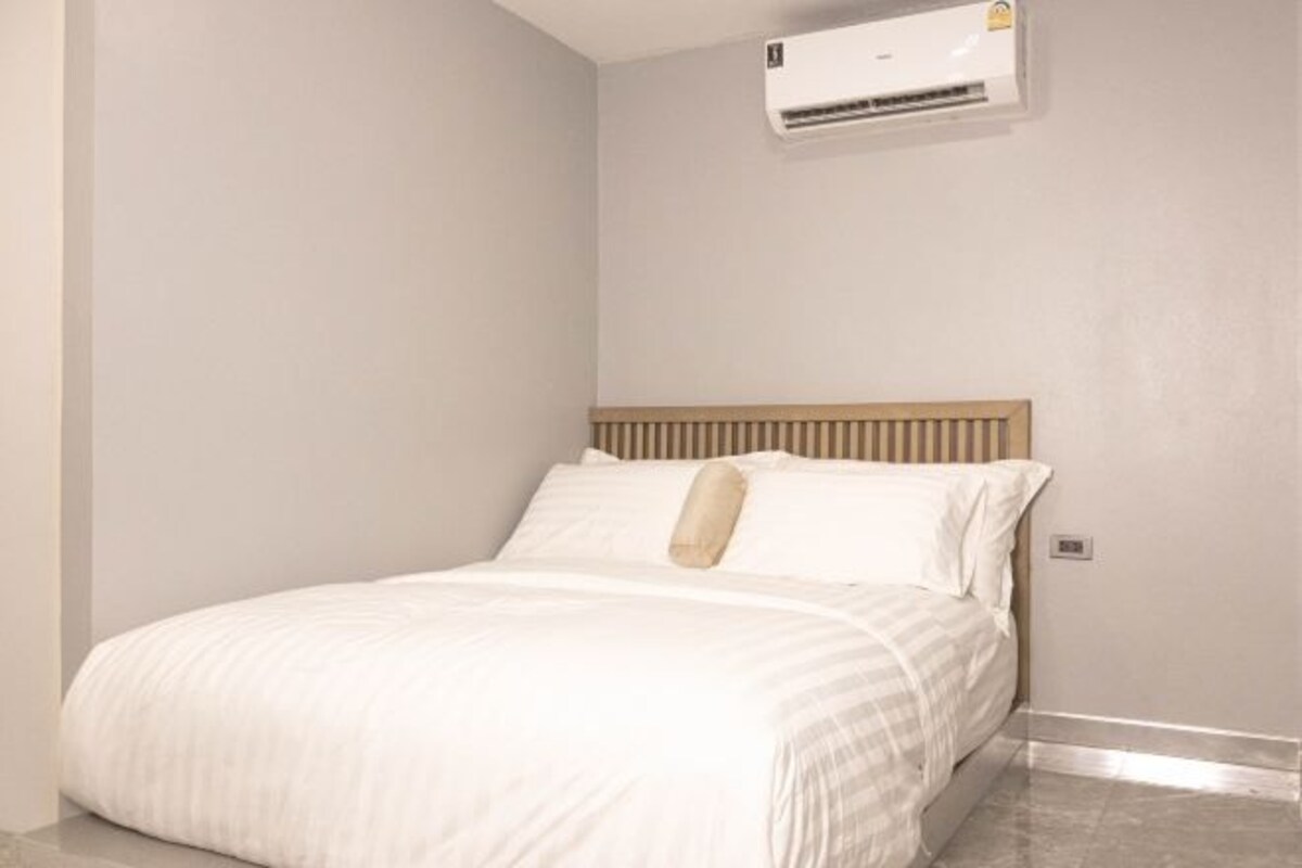 A bedroom with a bed, a wooden headboard, and an air conditioning unit on the wall.