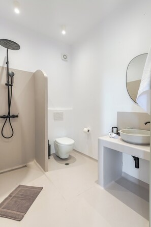 A modern bathroom with a shower, toilet, and sink. - Psathaki  (Kimolos)