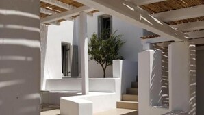 A modern architectural design with a staircase leading to a covered area, white walls, and a wooden ceiling. - Psathaki  (Kimolos)