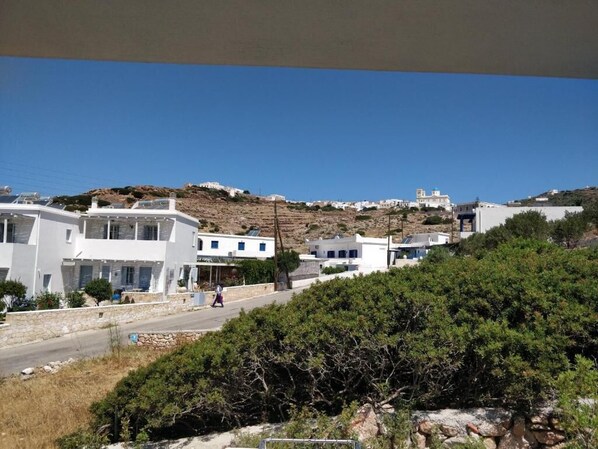A coastal village with white buildings, a road, and greenery.