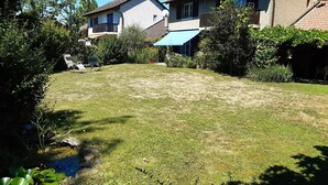 Un quartier résidentiel avec une pelouse, un petit étang et deux maisons équipées d’antennes paraboliques.