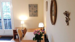 Une pièce avec une table en bois, deux lampes, un vase de fleurs, un tableau encadré et un miroir au mur.