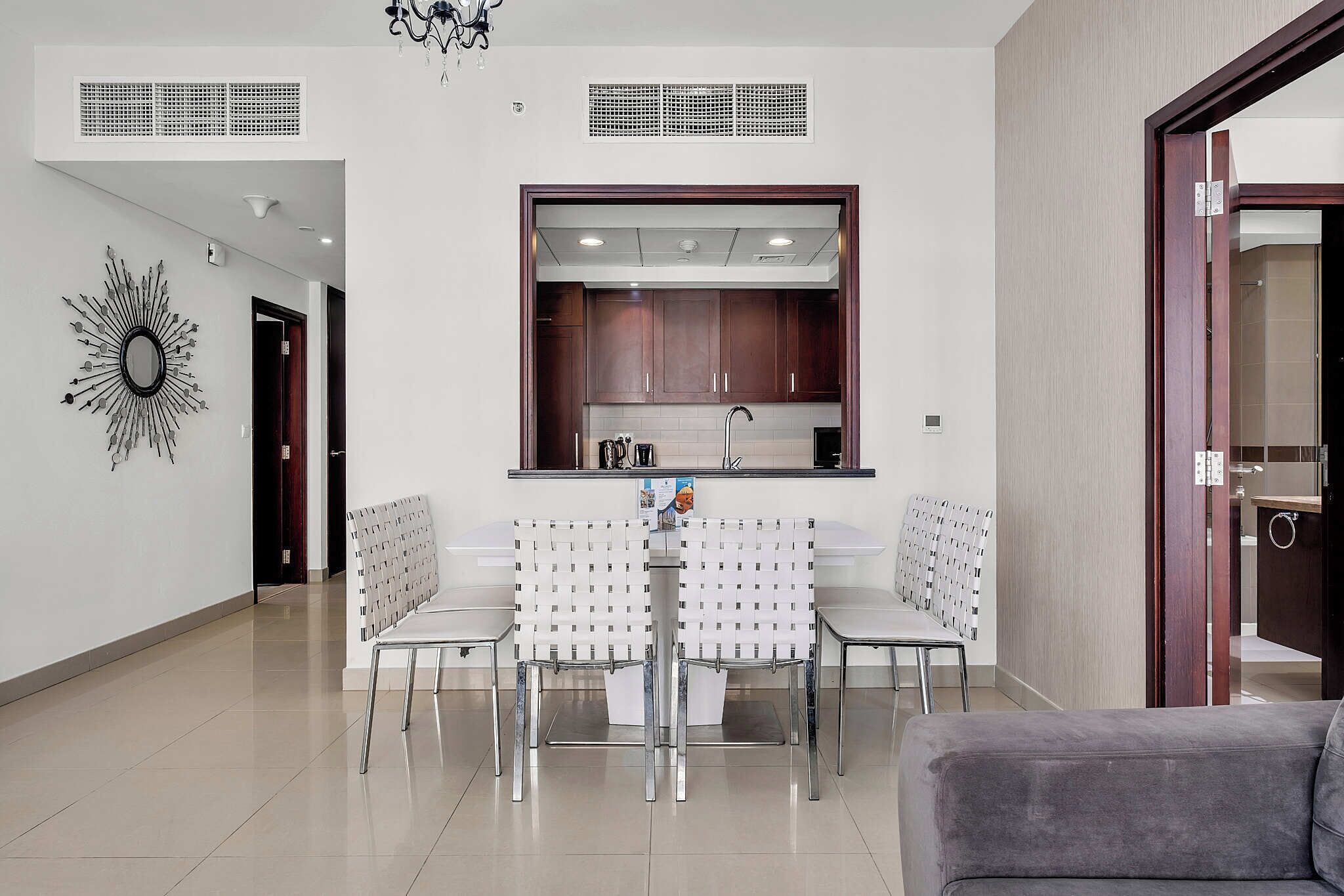 A modern kitchen with wooden cabinets, a built-in sink, and a dining area with a white table and chairs.
