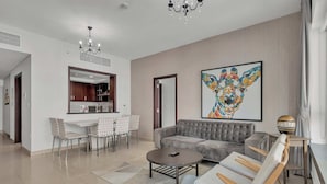 Un salon moderne avec un canapé gris, une table basse ronde et un coin repas comprenant une table et des chaises blanches.