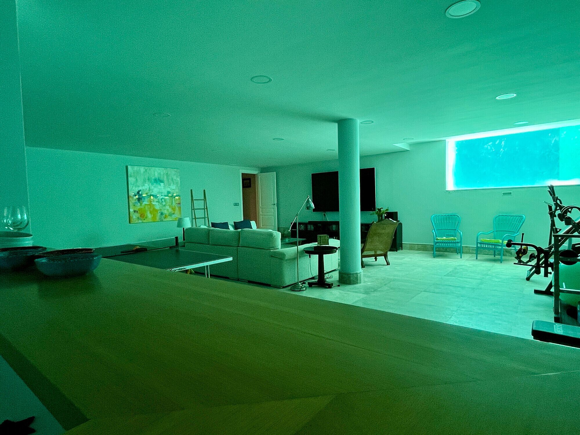 Una sala de estar moderna con un sofá, una mesa de centro y sillas. Hay un televisor y un cuadro en la pared.