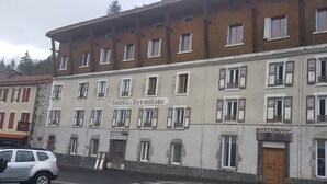 A historic building with a sign reading "Hotel Hermitage." It features multiple windows with shutters, a stone facade, and a traditional architectural style. - Quiet, independent double room facing the forest (Saint-Nectaire)