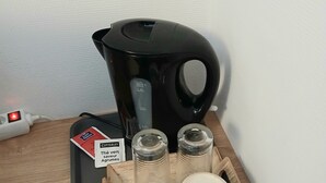 A coffee maker, a tray with mugs and glasses, and a power strip on a wooden table. - Quiet, independent double room facing the forest (Saint-Nectaire)