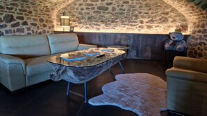 A cozy room with a stone wall, a sofa, a glass coffee table, and a teddy bear.