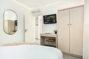 A modern bedroom with a bed, a desk with a chair, a TV mounted on the wall, and a wardrobe. - Royal Park Apt Resort by Sea N Rent (Eilat)