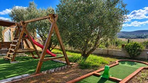 Ein Minigolfplatz mit einer hölzernen Schaukel und einer roten Rutsche im Hintergrund.