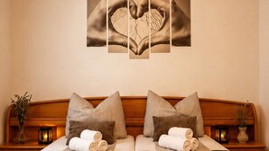 A neatly made bed with a wooden headboard, two pillows, and rolled towels. - Family Home Iskra (Bulic)