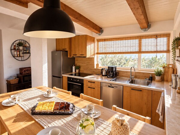 A modern kitchen with wooden cabinets, a stainless steel refrigerator, and a coffee maker.