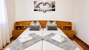 Ein Doppelbett mit gemusterten Bettdecken, zwei Nachttische und ein Bild an der Wand darüber.