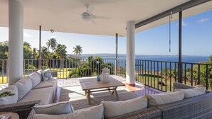 Un balcón amplio con vistas al mar, amueblado con un sofá, una mesa y una silla.