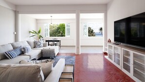 Una sala moderna con sofá, televisor y comedor con mesa y sillas.