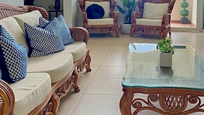 A spacious living room with a sofa, two armchairs, and a glass coffee table.
