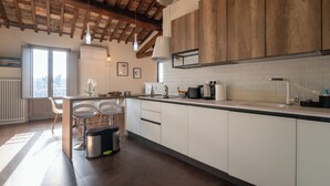 A modern kitchen with white cabinets, a wooden ceiling, and a large window.