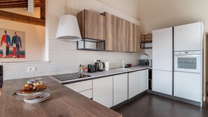 A modern kitchen with white cabinets, a wooden countertop, and a built-in oven.