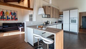 A modern kitchen with a central island, white cabinets, and a wooden ceiling.