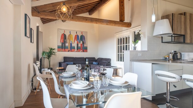 A modern dining area with a glass table, white chairs, and a wooden ceiling.