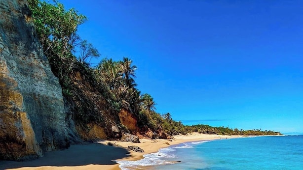 Una spiaggia limpida con acque calme, una riva sabbiosa e un promontorio roccioso.