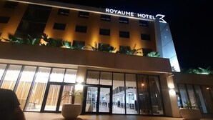 L’extérieur de l’HÔTEL ROYAUME présente un design moderne, de grandes fenêtres en verre et des plantes en pot.