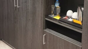 En garderob med mörk träfinish, en hylla med olika föremål och en dörr med ett handtag.