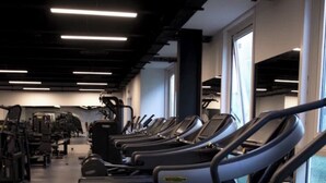 A gym with multiple treadmills aligned in rows, exercise equipment, and large windows allowing natural light. - Royaume Hotel Aeroport (Algiers)