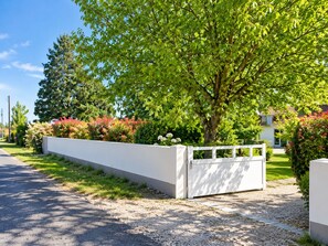 Ein Wohnhof mit weißem Zaun, einem Baum und einem Haus im Hintergrund.