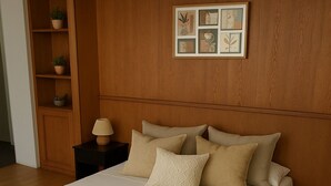 Une chambre à coucher avec un grand lit, une tête de lit en bois, une table de chevet avec une lampe et un tableau encadré au mur.