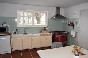 Una cocina con estufa, lavaplatos y ventana.