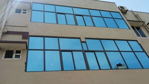 Un immeuble à plusieurs étages doté de grandes fenêtres et dont les éléments structurels, tels que les tuyaux et les conduits de ventilation, sont apparents.