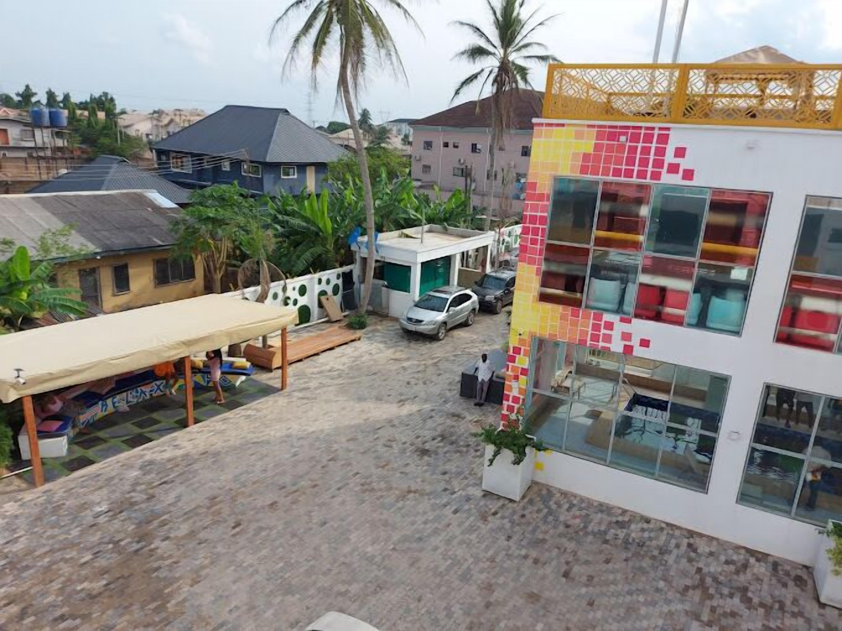 A residential area with a colorful building, a covered outdoor seating area, and a parked car.