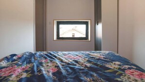 A bedroom with a bed, a window, and a view of a building outside. - Apartman Mrkonjic-Pula (Pula)