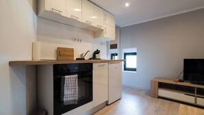 A modern kitchen with white cabinets, a built-in oven, and a wooden countertop. - Apartman Mrkonjic-Pula (Pula)