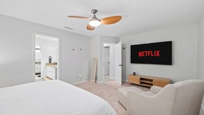 A bedroom with a bed, a ceiling fan, a TV mounted on the wall, and a wooden cabinet. - This house is a 3 bedroom(s), 2 bathrooms, located in Richardson, TX. (Richardson)