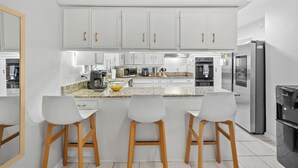 A modern kitchen with white cabinets, a granite countertop, and three bar stools. - This house is a 3 bedroom(s), 2 bathrooms, located in Richardson, TX. (Richardson)