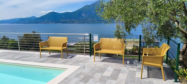 A poolside area with chairs and a view of a lake and mountains.