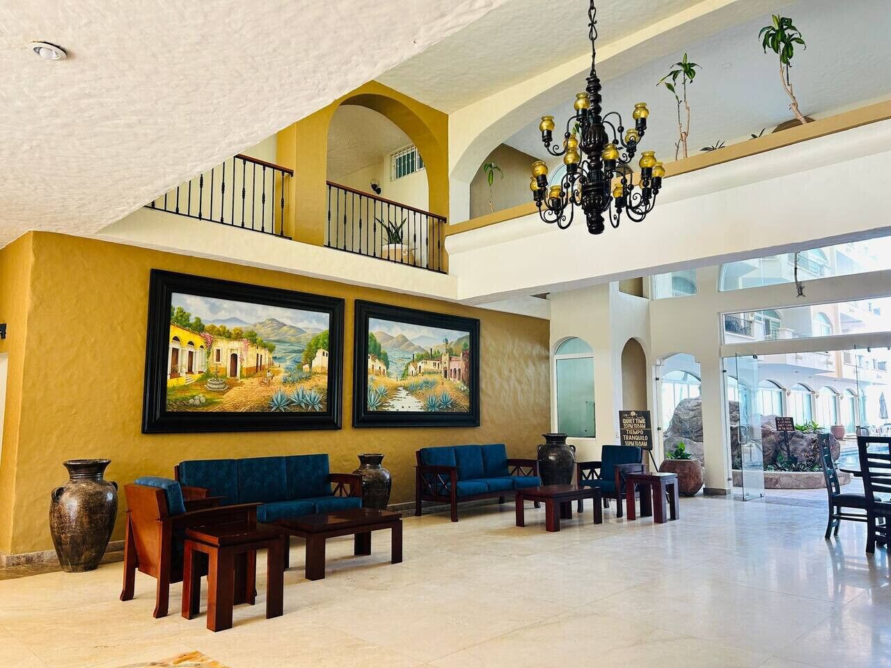 A spacious lobby with a high ceiling, a balcony, and two large landscape paintings.
