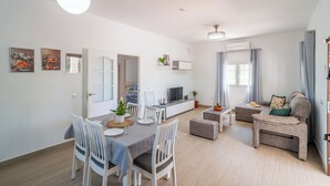 Un salon moderne comprenant un coin repas, un ensemble de canapés et un téléviseur.