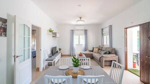 Un salon moderne comprenant un coin repas, un ensemble de canapés et un téléviseur.