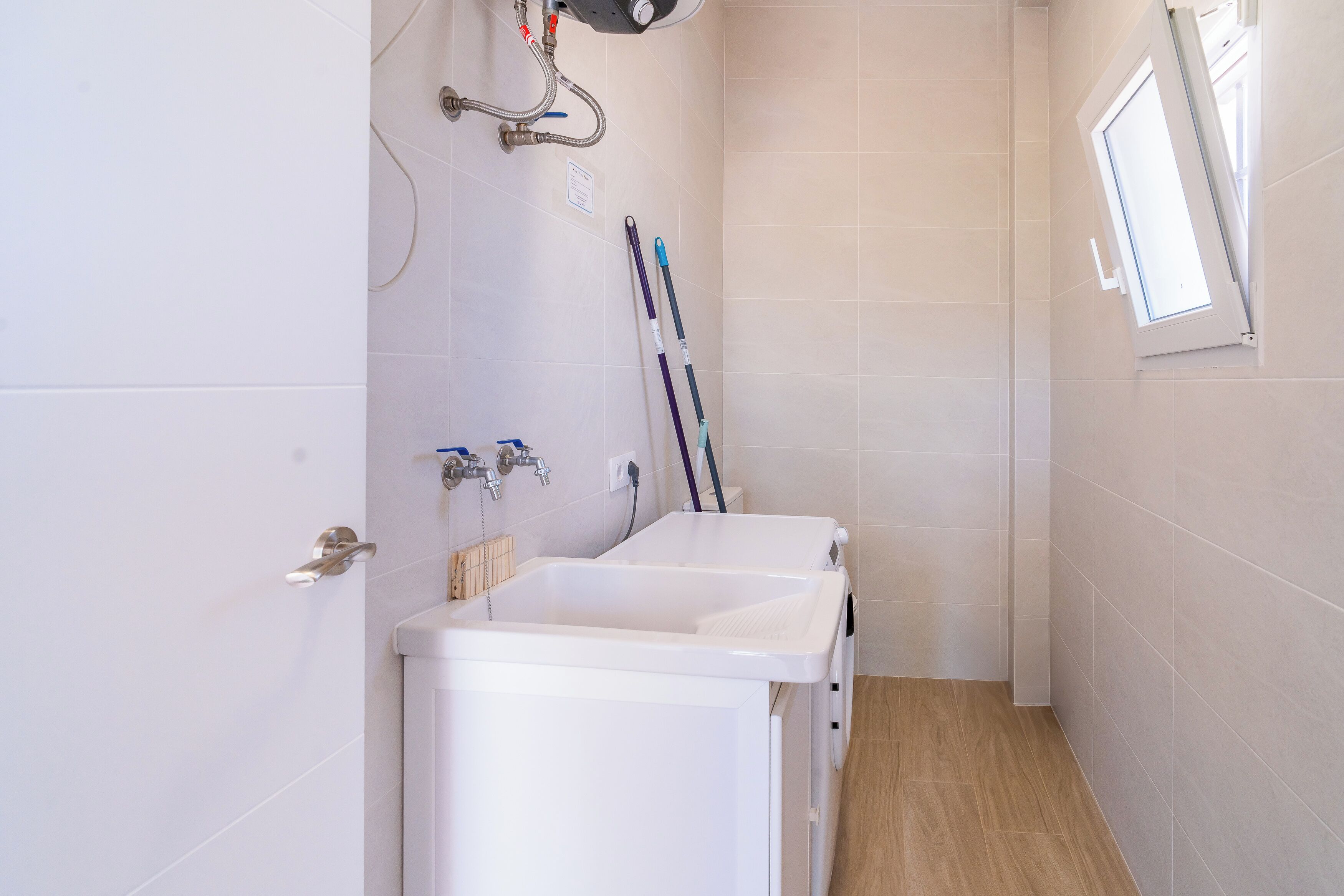 A small, clean bathroom with a sink, a mirror, and a window.