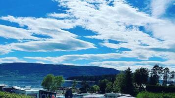 A campground with RVs parked near a lake, surrounded by trees and hills in the background.