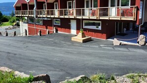 A red building with a balcony, a small garden, and a view of the mountains. - Utvika Gård & Camping (Hole)