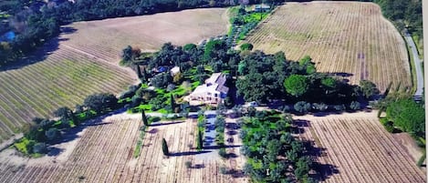 An aerial view of a property with a central house surrounded by fields and trees.