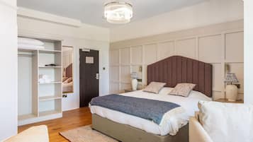 A bedroom with a large bed, a wardrobe, a bedside table, and a chandelier.