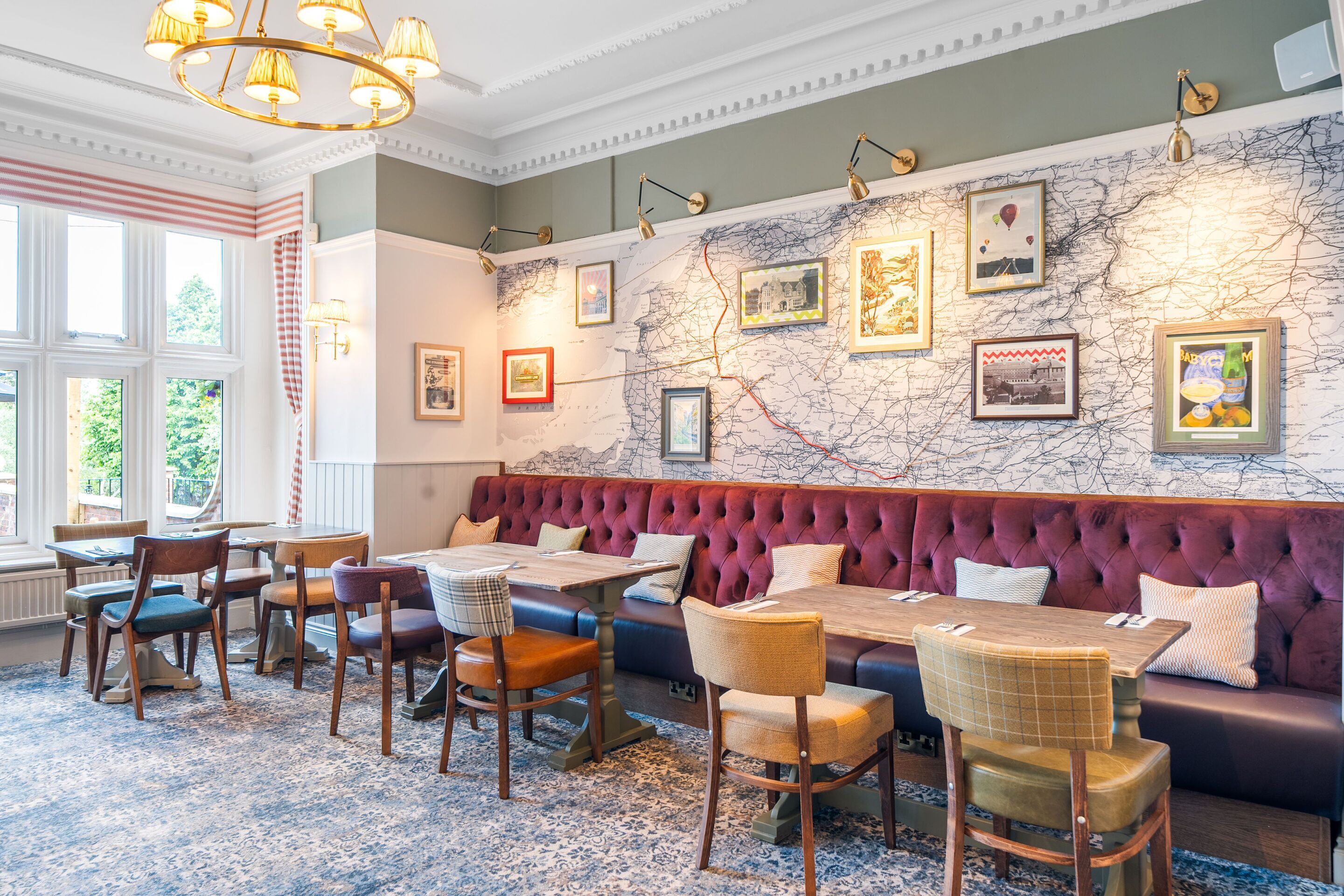 A restaurant with a marble wall, framed pictures, and a red upholstered bench.
