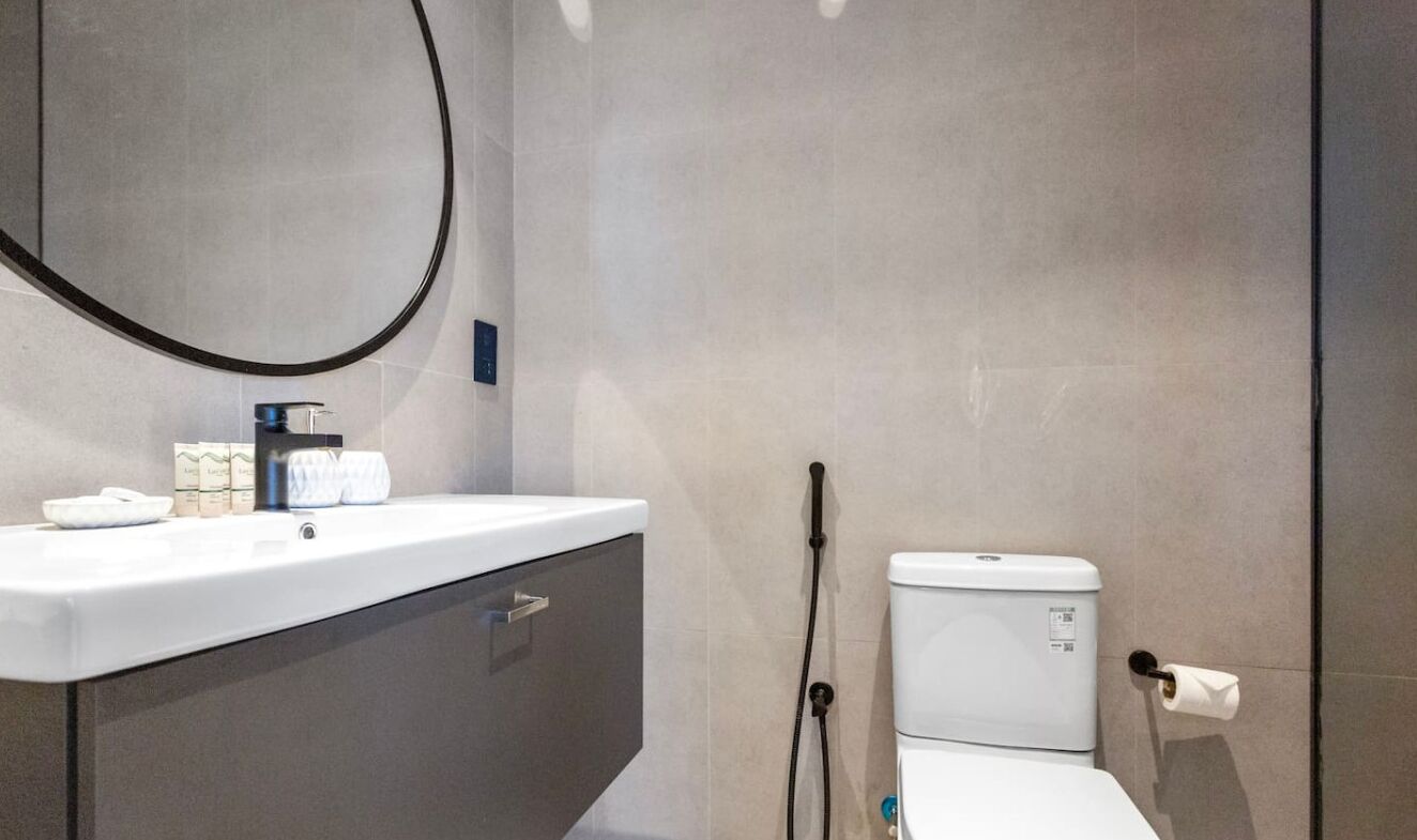 A modern bathroom with a white sink, a toilet, and a towel rack.